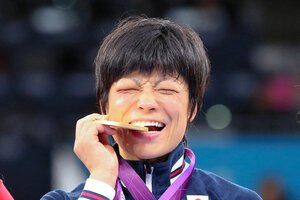 2012年のロンドン五輪レスリング女子48キロ級で優勝し、金メダルをかじるポーズをする小原日登美