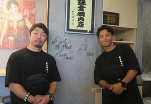1日店長を務めた鎌倉精肉店内にサインしたWBO世界バンタム級王者武居由樹(右)と八重樫東トレーナー