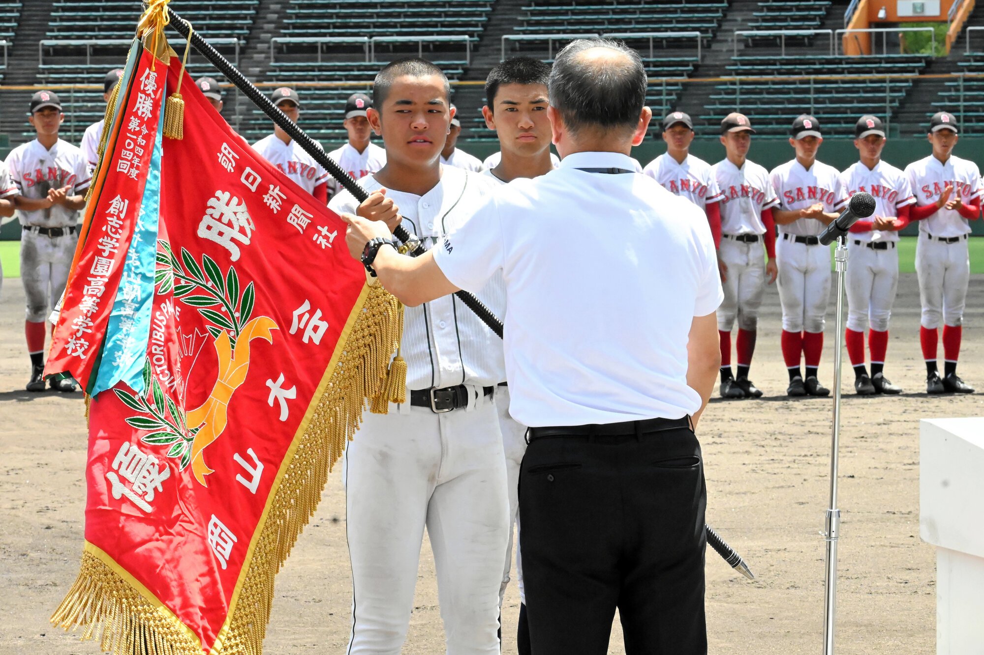 優勝旗を受け取る岡山学芸館の国近泰獅主将=2025年7月27日午後0時59分、マスカット、渡辺翔太郎撮影