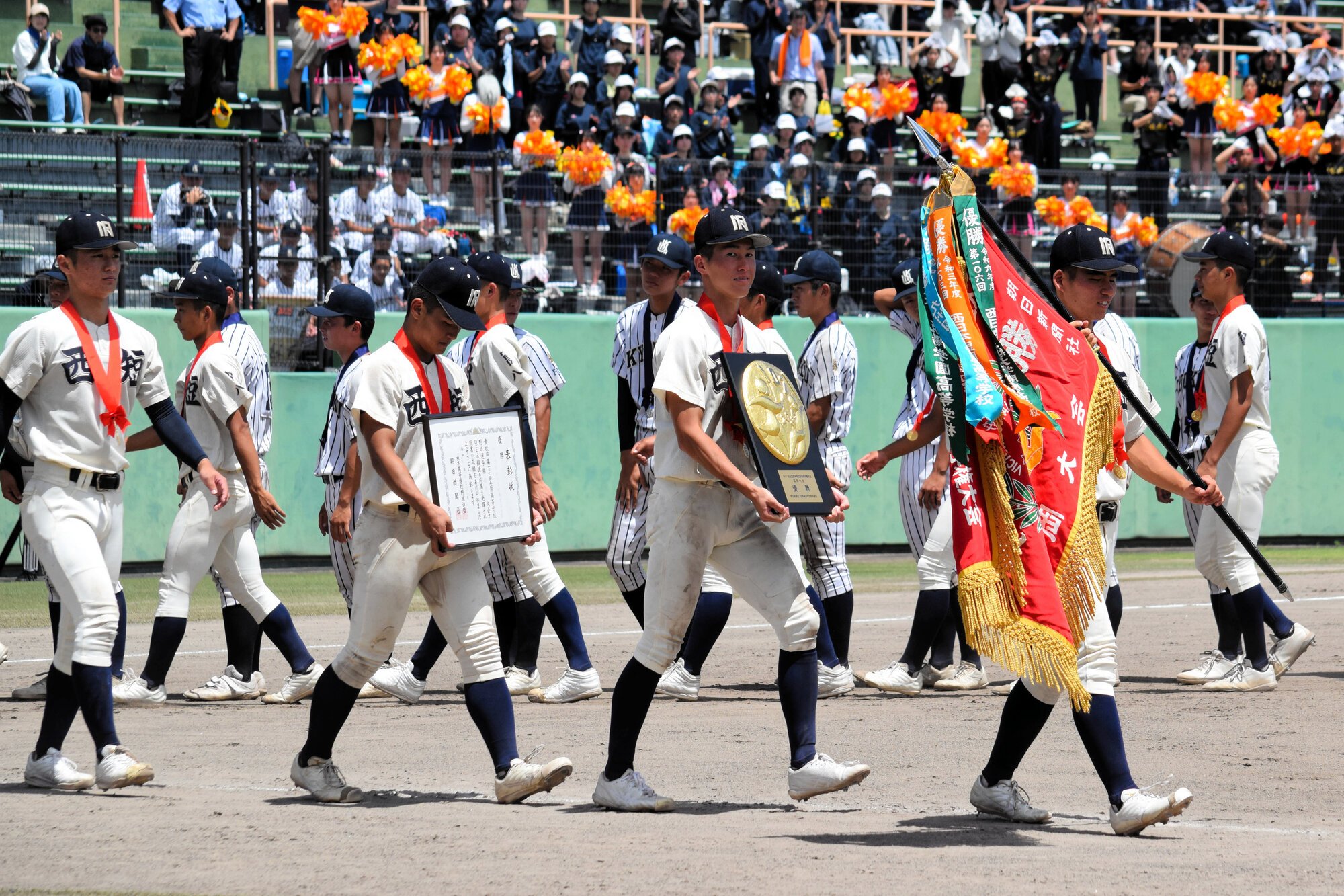 優勝旗を手に行進する西日本短大付の選手たち=2025年7月27日午後1時8分、久留米市、八尋紀子撮影