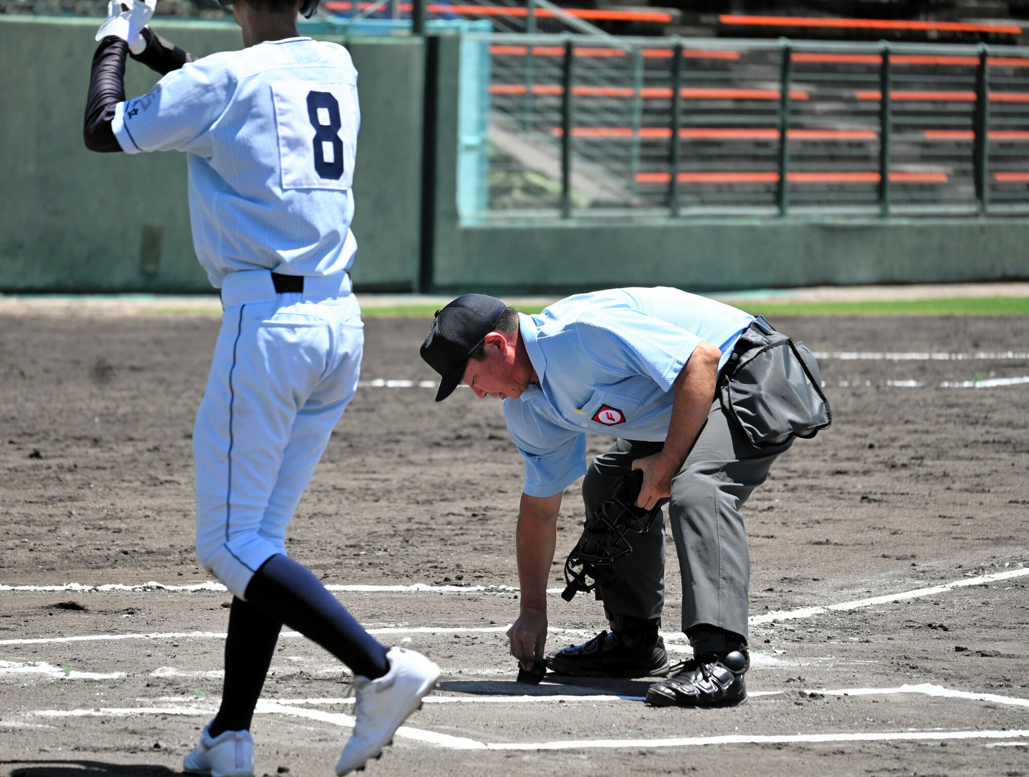 ホームベースの土を払う村井啓一郎さん(右)=2025年7月20日午後0時9分、むつみ、鈴木史撮影