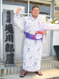 部屋宿舎での新十両会見後、花束を手に部屋の看板の隣でガッツポーズをつくった西ノ龍