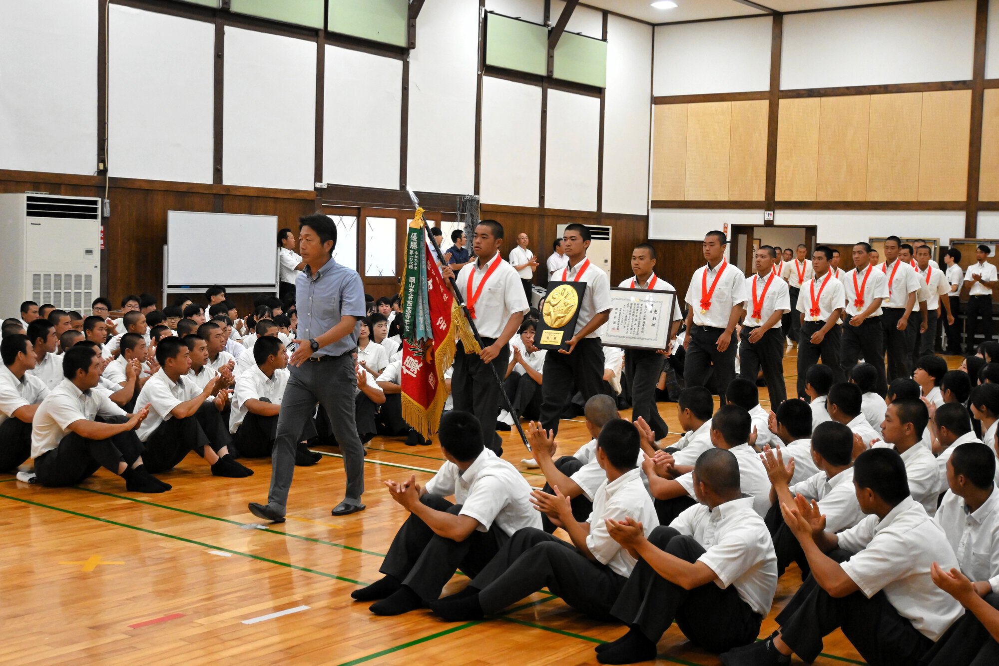 壮行式で優勝旗や盾を手に入場する岡山学芸館の選手ら=2025年7月30日午前8時45分、岡山市東区、上山崎雅泰撮影