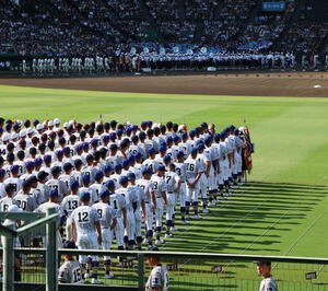 開会式で西日を受けて影が伸びる中を入場行進する選手たち(撮影･加藤哉)