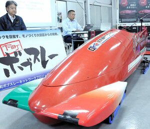 イタリアの男子2人乗りチームが使うそりと黒坂浩太郎委員長(右)。改良するため日本に戻ってきた