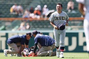 仙台育英対鳥取城北　8回裏の守備を終えたところで足をつり、担架で運ばれる仙台育英･田山(左)とベンチへ戻る須江監督(撮影･前田充)
