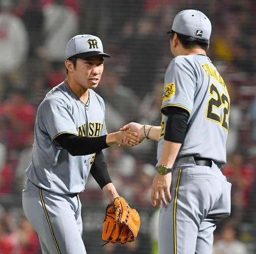 広島対阪神　セリーグ新記録となる39試合連続無失点を達成した石井(左)は藤川監督と握手を交わす(撮影･岩下翔太)