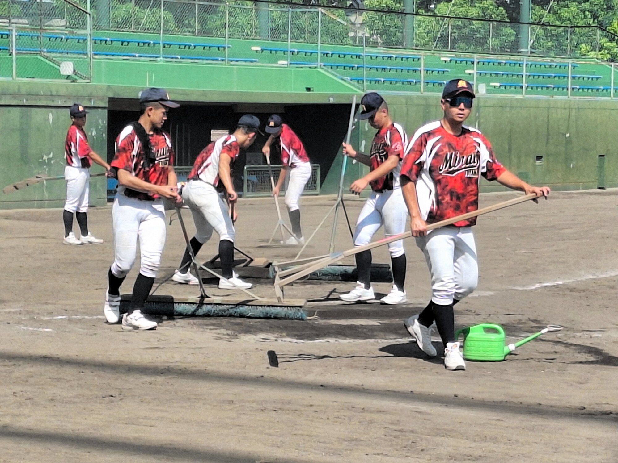 大会本部から割り当てられた球場で、選手と一緒に整備する角鴻太郎監督(右)=2025年8月9日、兵庫県西宮市、前多健吾撮影