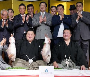 千秋楽パーティーで関係者の祝福を受けながらお祝いのタイを持つ大の里。右は師匠の二所ノ関親方(撮影･小沢裕)
