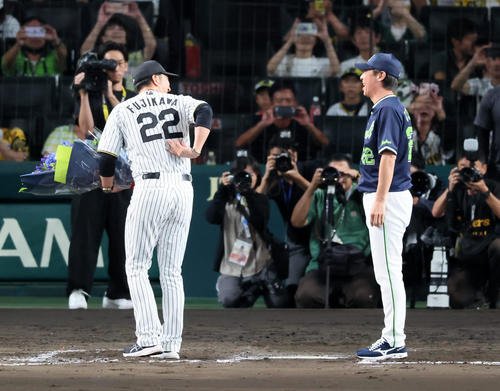 阪神対ヤクルト　試合後ヤクルト高津監督に花束を手渡す阪神藤川監督(左)は背中の背番号22を見せて言葉をかける(撮影･加藤哉)