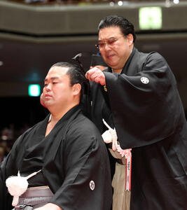 師匠の境川親方(右)に止めばさみを入れてもらう振分親方(撮影･鈴木正人)