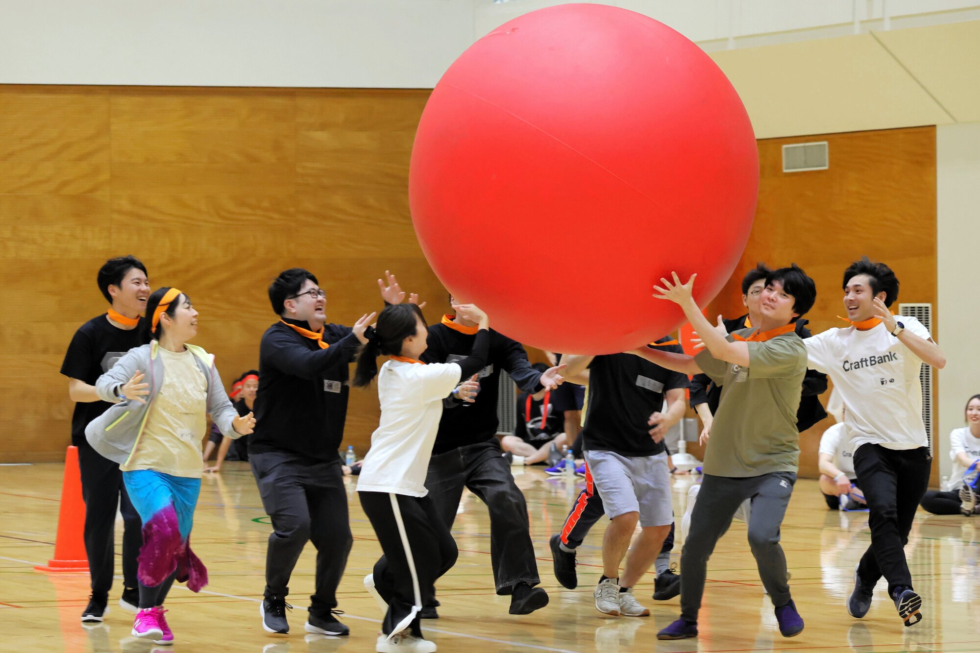 会社の運動会で協力して大玉を運ぶ参加者たち=2025年4月10日、東京都大田区、清水優志撮影