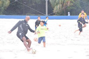 ビーチサッカー体験で子どもたちとボールを追う茂怜羅オズ(左)(撮影･泉光太郎)