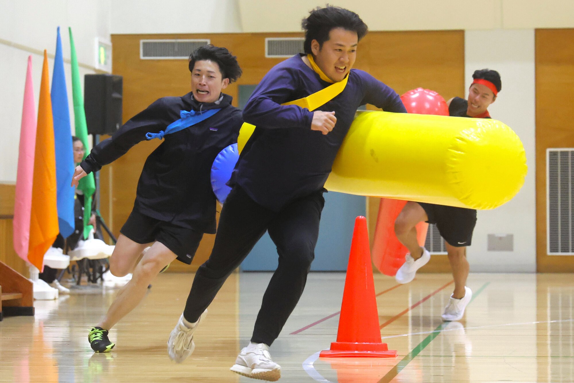 巨大なバトンでリレーする企業運動会の参加者たち=2025年4月10日、東京都大田区、清水優志撮影