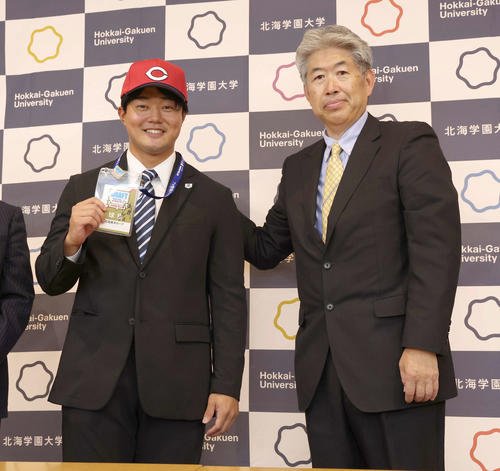 広島から4位指名された北海学園大の工藤(左)は近藤スカウトから指名あいさつをうけ笑顔を見せる(撮影･黒川智章)