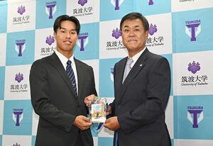 指名あいさつを受けた阪神ドラフト3位の筑波大･岡城(左)は平塚スカウトから藤川監督のサイン入りドラフト会議のパスを受け取る(撮影･滝沢徹郎)