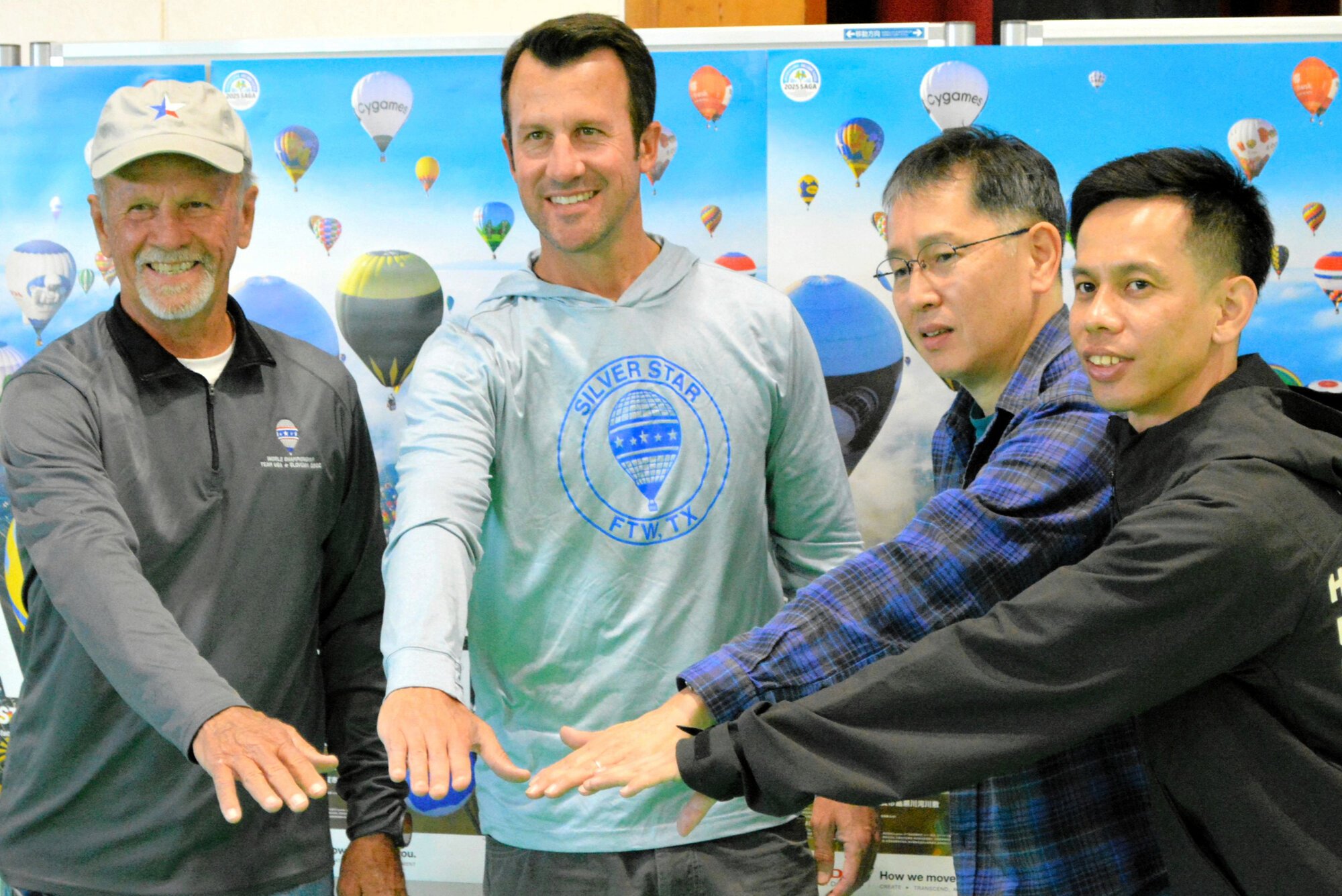 報道陣の前で手を合わせる4人。左からジョー･ハートシルさん、レット･ハートシルさん、片平史郎さん、上田諭さん=2025年10月29日、佐賀市久保田町新田、石田一光撮影