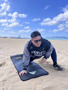 砂浜でストレッチするソフトバンク山川(撮影･佐竹英治)