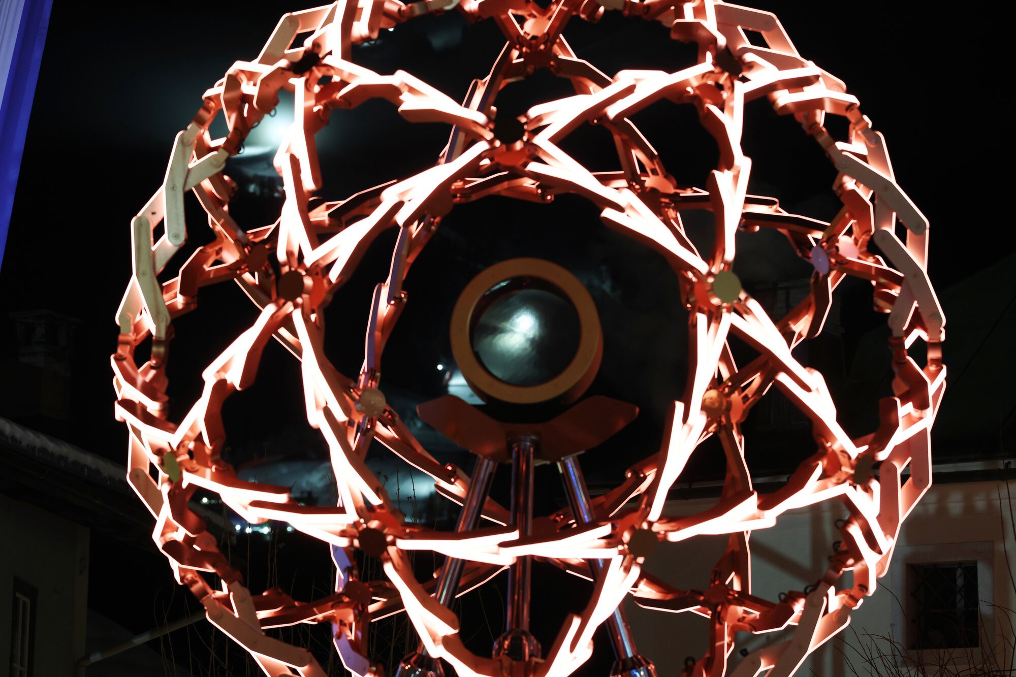 赤くライトアップされた聖火台。山間部の照明が聖火台越しに見えた=2026年2月2日午後6時25分、イタリア･コルティナダンペッツォ、小林一茂撮影