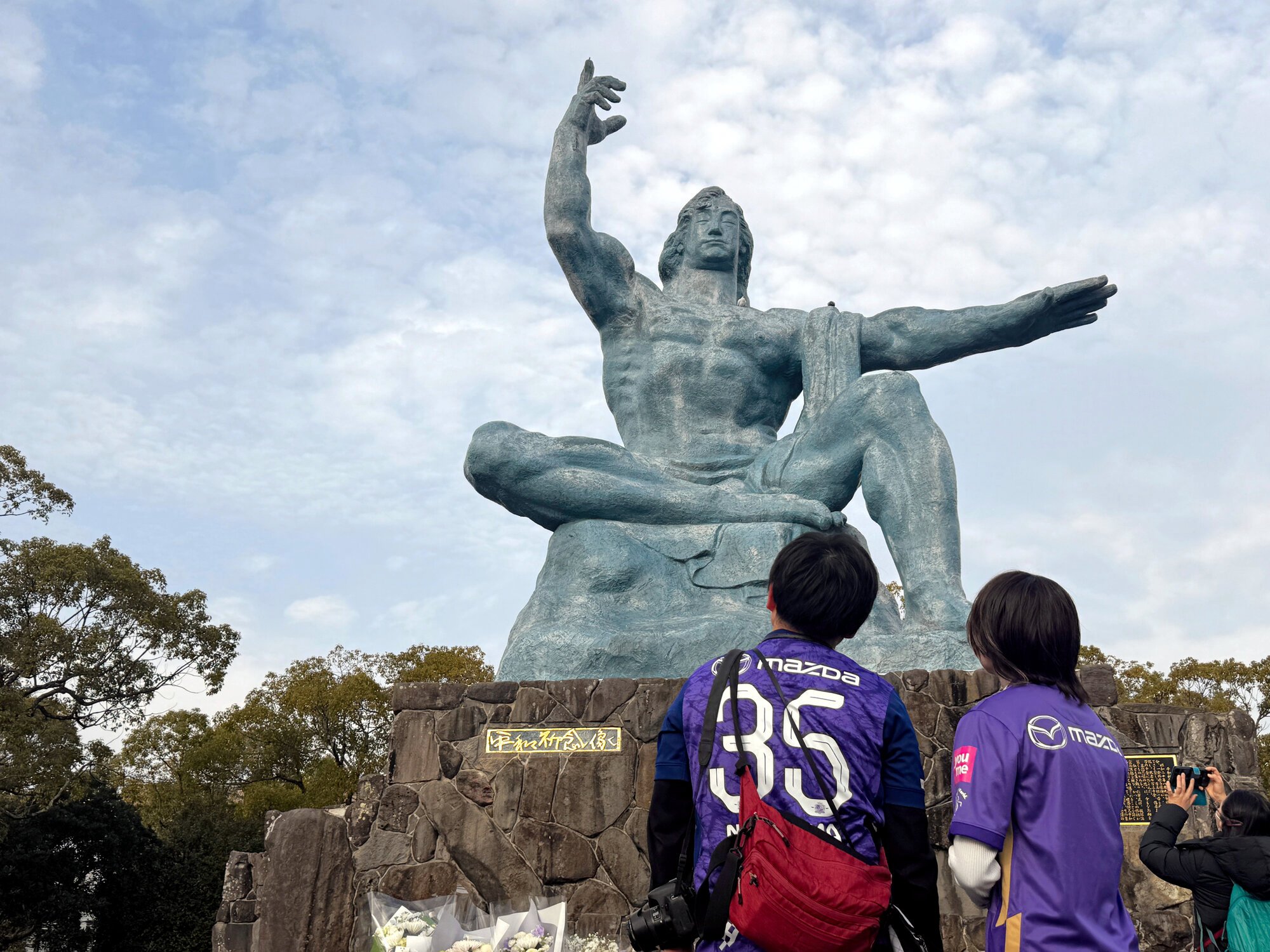 長崎の平和公園で平和祈念像を見上げる広島サポーター=2026年2月6日午後3時49分、長崎市松山町、榧場勇太撮影