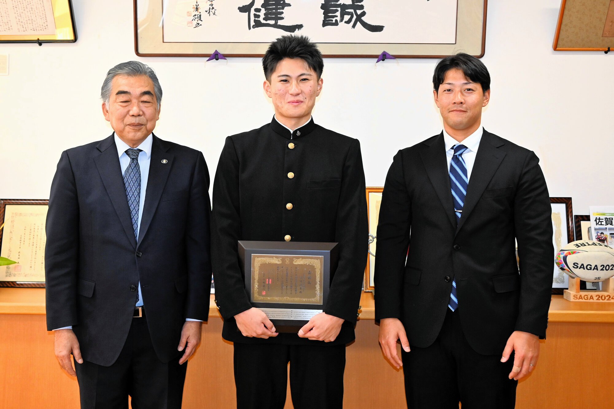 表彰盾を持つ宮崎淳多さん(中央)と本村祥次監督(右)、原口哲哉佐賀県高野連会長=2026年1月28日、佐賀市緑小路