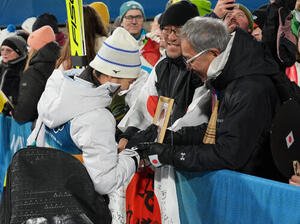 女子個人ラージヒルを終え、母信子さんの写真に触れる丸山希。右は父守さん(撮影･パオロ　ヌッチ)