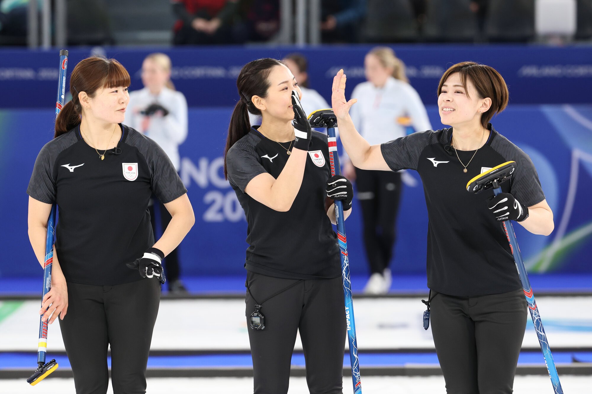 中国戦の第3エンド、ハイタッチをする小野寺佳歩(中央)と近江谷杏菜。右は小谷優奈=小林一茂撮影