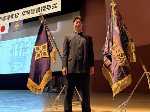 横浜の卒業式で、センバツ優勝旗の前で写真に納まるロッテの奧村頼(撮影･保坂淑子)