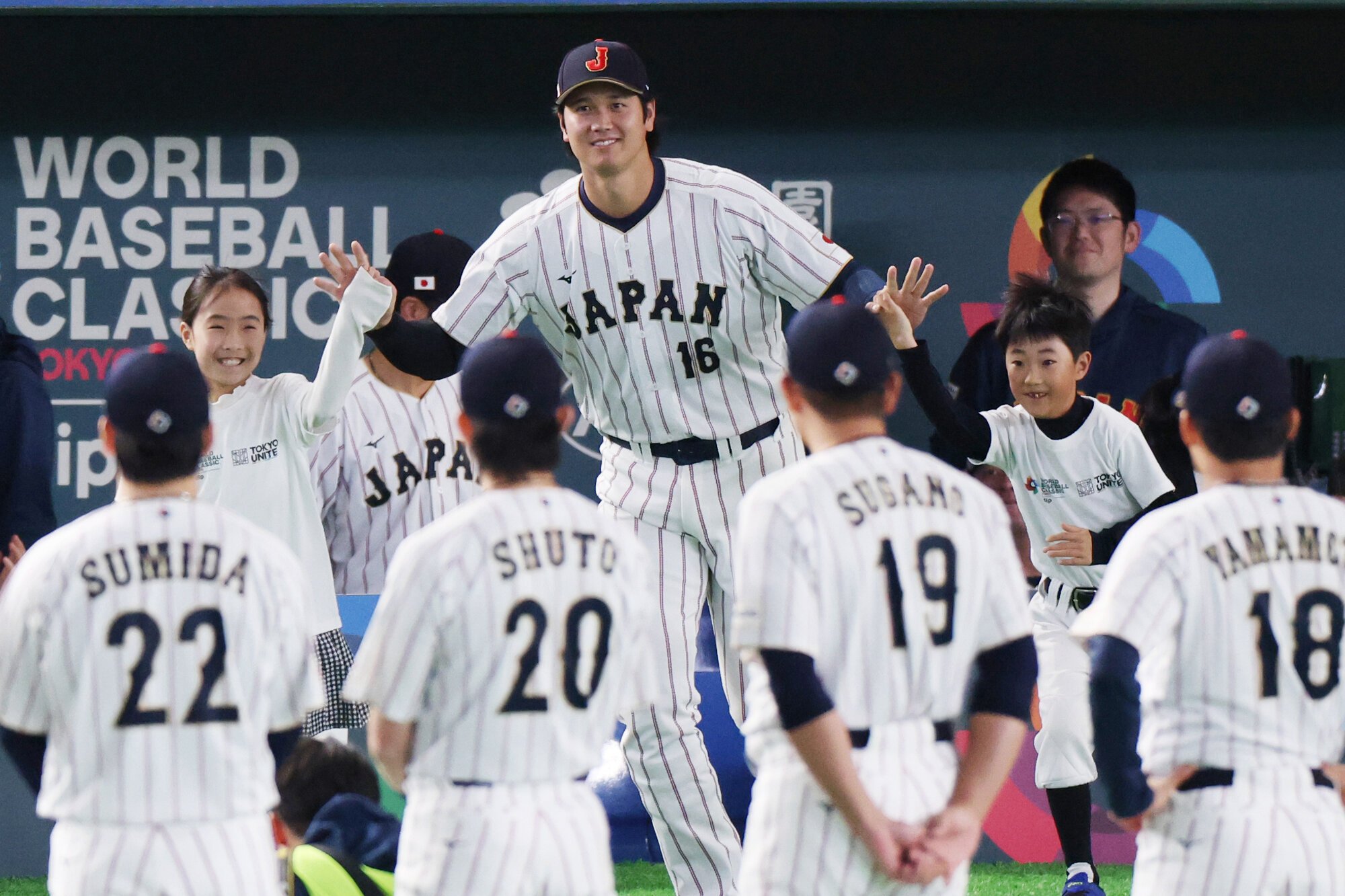 試合前、子どもたちと手をつないで整列に向かう大谷翔平(中央)=友永翔大撮影