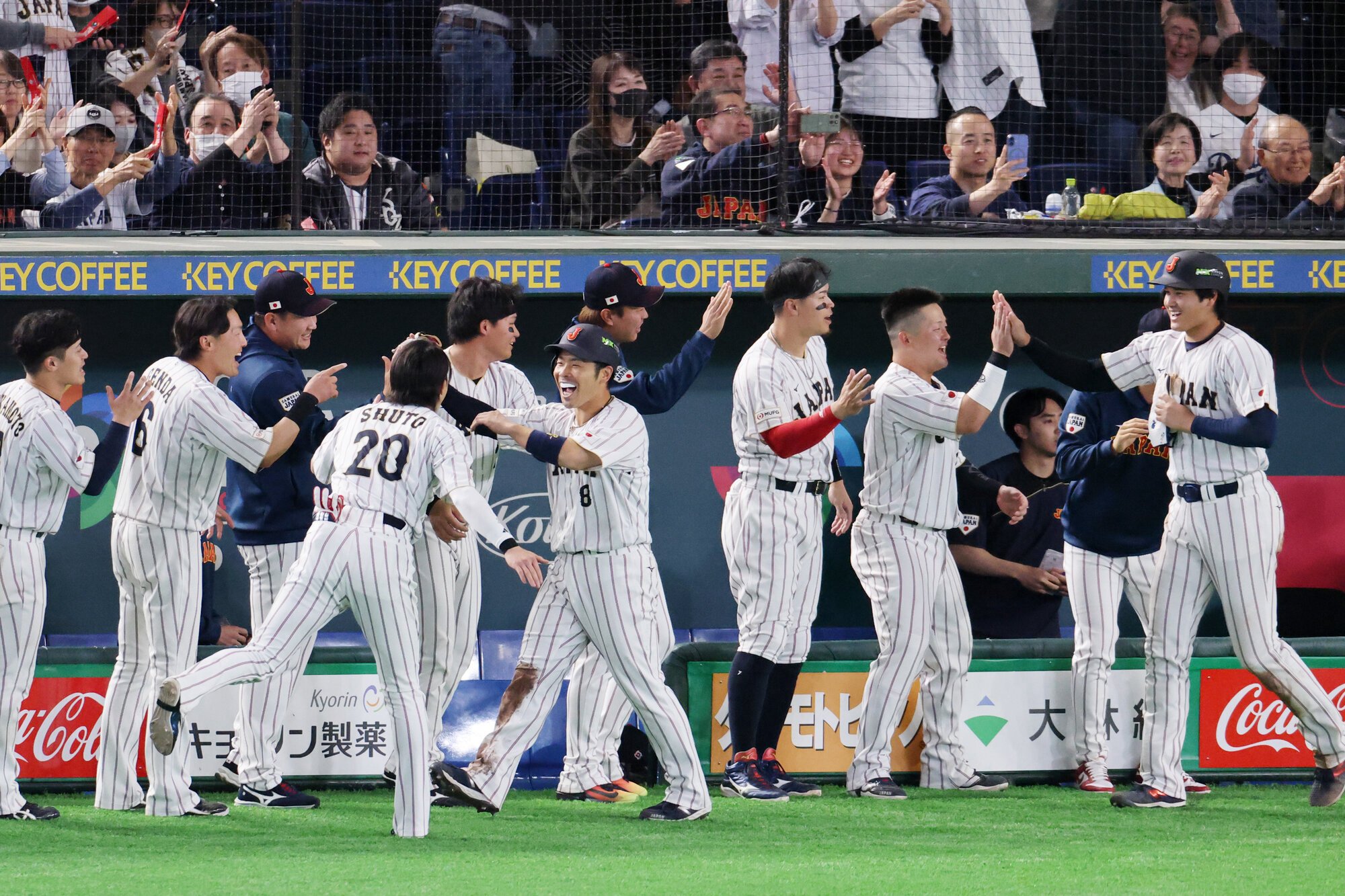 七回裏日本2死満塁、吉田正尚の2点適時打で生還し、ベンチ前で喜ぶ二塁走者近藤健介⑧と三塁走者大谷翔平(右端)=友永翔大撮影