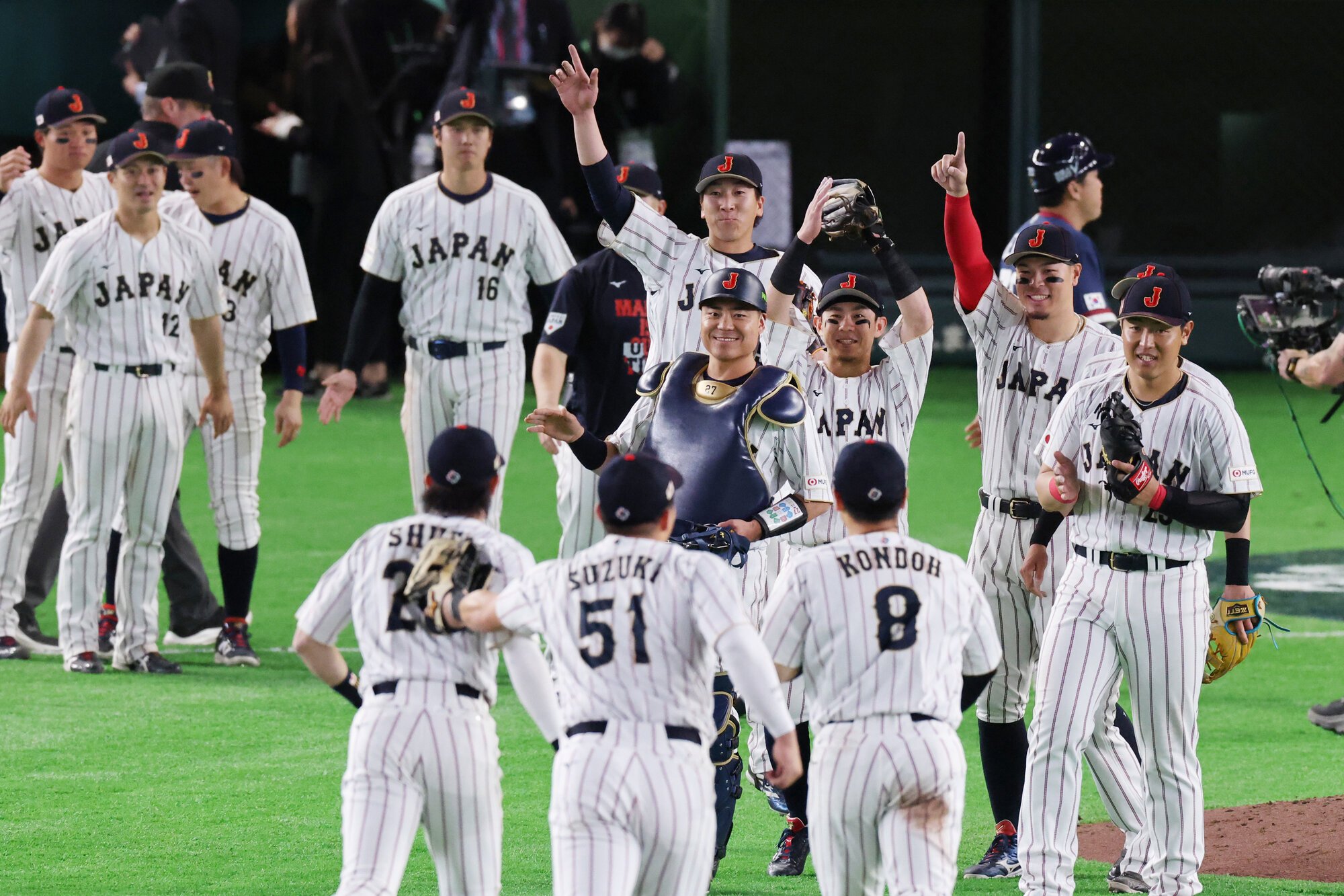 韓国に勝利し、好守備を見せた中堅手の周東佑京(手前左)を待ち受ける大勢(中央奥)ら=友永翔大撮影