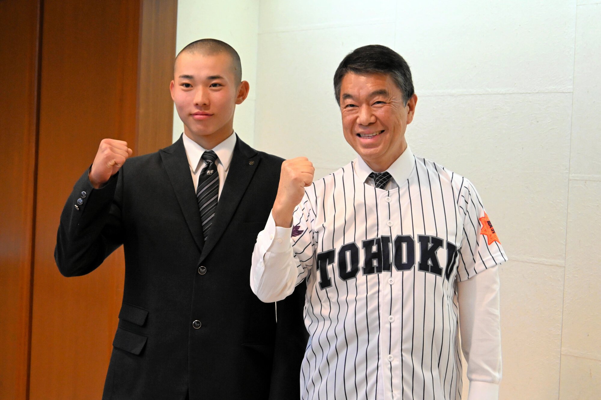 村井嘉浩知事(右)は、松本叶大主将からユニホームをもらうと、笑顔で袖を通した=2026年3月10日午後1時40分、仙台市青葉区の宮城県庁、三村悠撮影