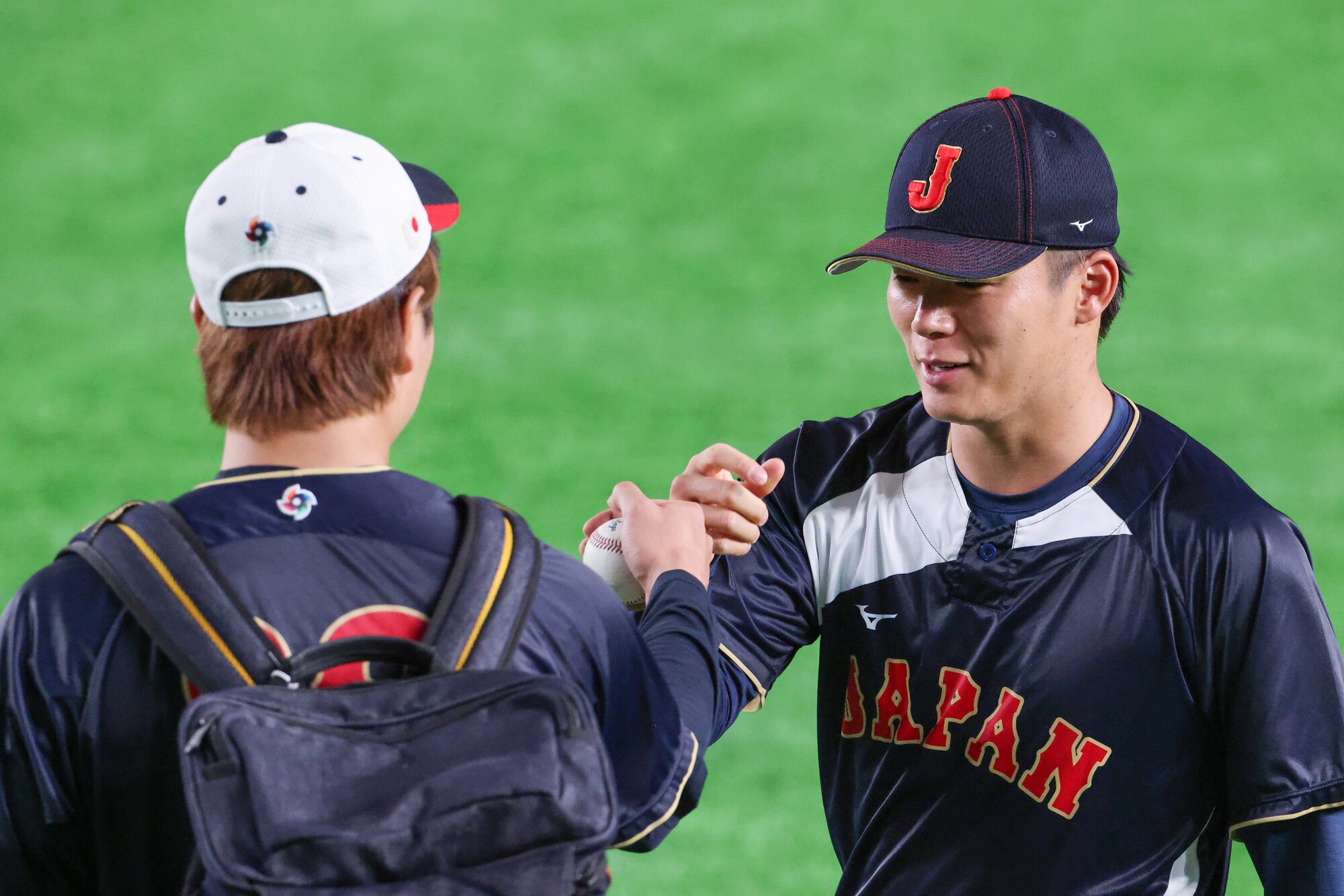 7日の韓国戦前の練習を終えて、高橋宏斗(左)とグータッチを交わす山本由伸=友永翔大撮影
