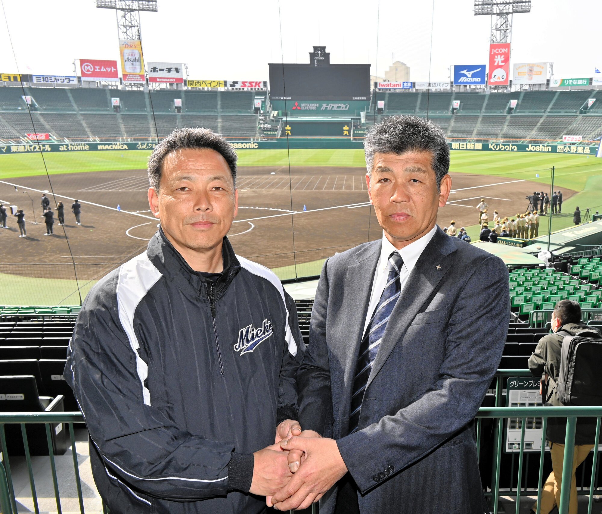 1回戦で顔を合わせる佐野日大の麦倉洋一監督(右)と三重の沖田展男監督=2026年3月18日、兵庫県西宮市の阪神甲子園球場、津布楽洋一撮影