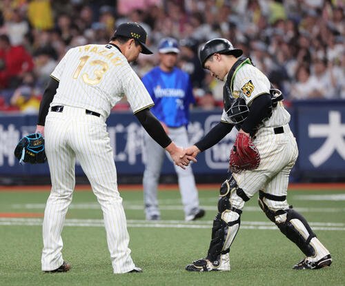 阪神対DeNA 9回表DeNA2死一、二塁、最後の打者を三振に打ち取った岩崎は坂本と握手(撮影･西尾就之)