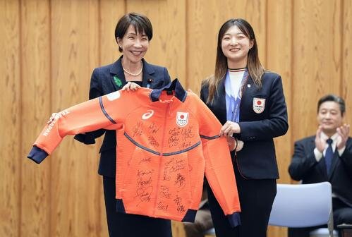 フィギュアスケート女子の坂本花織(右)からサイン入りのウエアを贈られ笑顔の高市首相(共同)