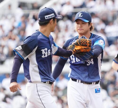 ロッテ対西武　7回途中から2番手で登板した甲斐野央(右)はこの回を無失点でしのぎ石井一成とグラブタッチ(撮影･小沢裕)