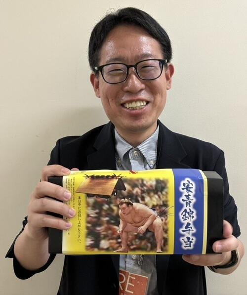 夏場所初日に販売された安青錦弁当を持つ本紙記者