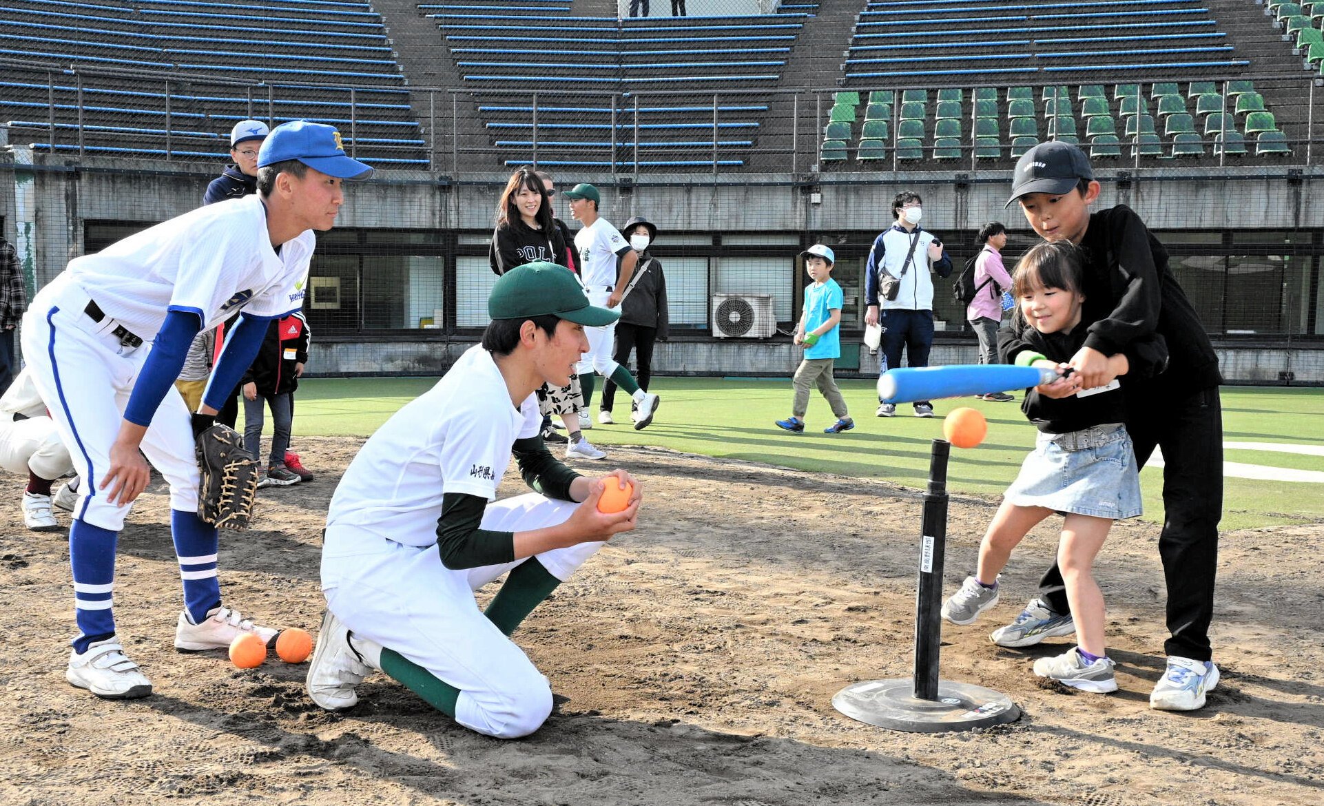 高校球児に教わりながら、ティーバッティングに挑戦するきょうだい=2026年5月23日、山形県新庄市、黒川和久撮影