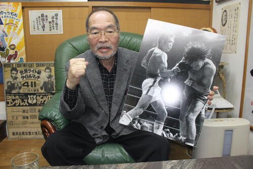 右アッパーでロハスを一発KOした5度目の防衛戦の写真パネルを手にガッツポーズを決めるガッツ石松さん(撮影･首藤正徳)