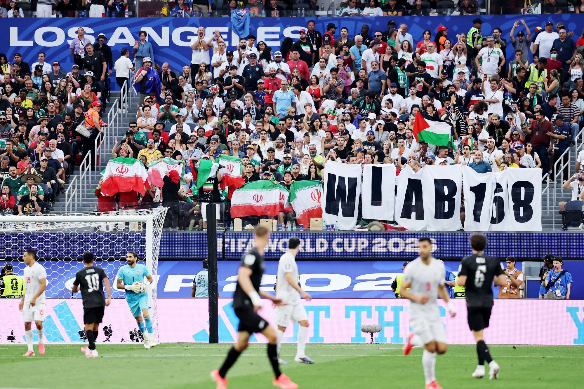 サッカーワールドカップ北中米大会　グループG　イラン―ニュージーランド　前半、米国とイスラエルによる攻撃で多数の子どもたちが犠牲になった都市名から付けられたイラン代表の愛称｢ミナブ168｣と書かれた横断幕を掲げる人も見られた=2026年6月15日、米国･ロサンゼルス、内田光撮影