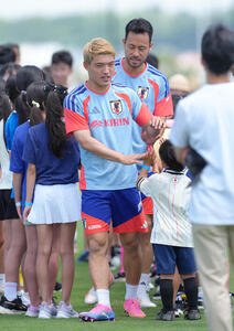 練習前、訪れた現地の子どもたちとタッチを交わす堂安律(撮影･足立雅史)