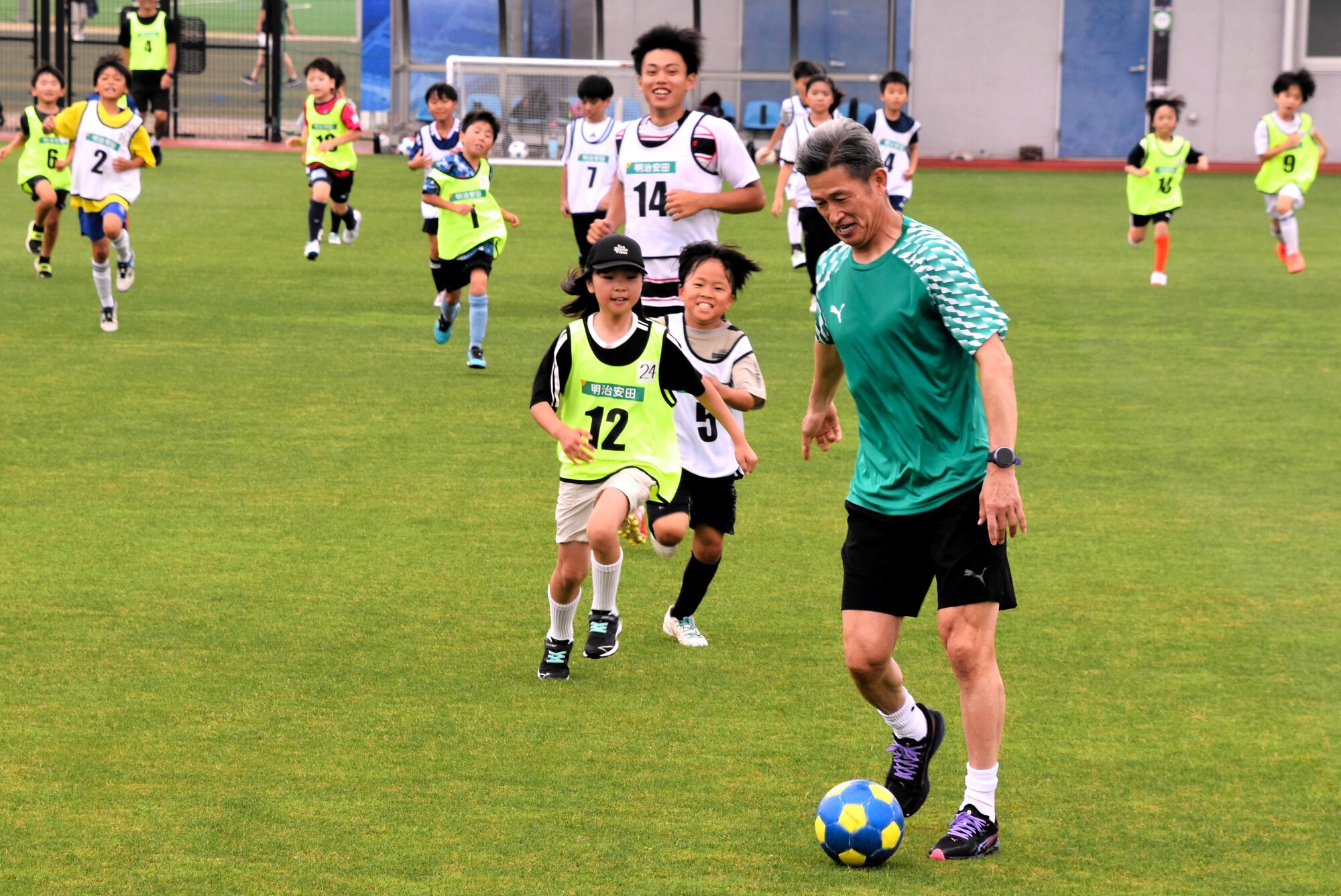 ミニゲームでドリブルする三浦知良選手(手前)。スピードを落として子どもたちを待つと、みんな追いかけてきた＝2026年6月20日午前、大阪府堺市堺区、杉田基撮影