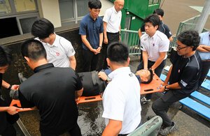 熱中症の患者を想定し、スタンドから担架で運び出す訓練を行った=2026年6月25日、熊本市中央区、伊藤隆太郎撮影