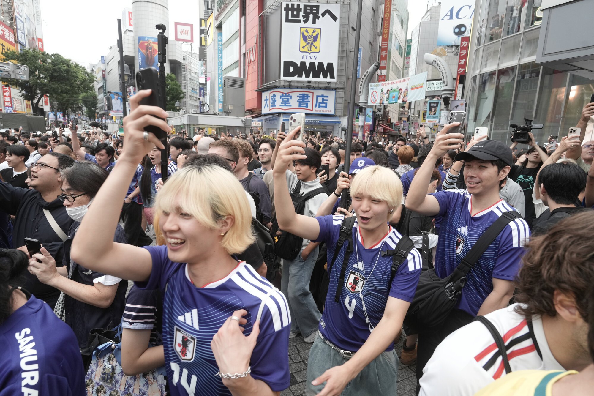 日本の決勝トーナメント進出が決まり、渋谷スクランブル交差点で喜ぶ人たち=2026年6月26日午前10時5分、東京･渋谷、竹花徹朗撮影