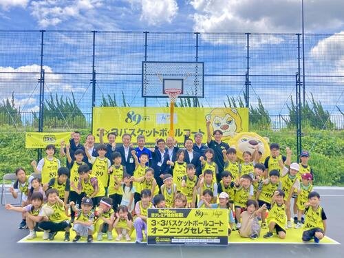 オープニングセレモニーで記念写真に納まるBプレミア仙台志村雄彦社長、阿部真冴橙、来賓とバスケ体験会に参加した児童たち(撮影･高橋香奈)