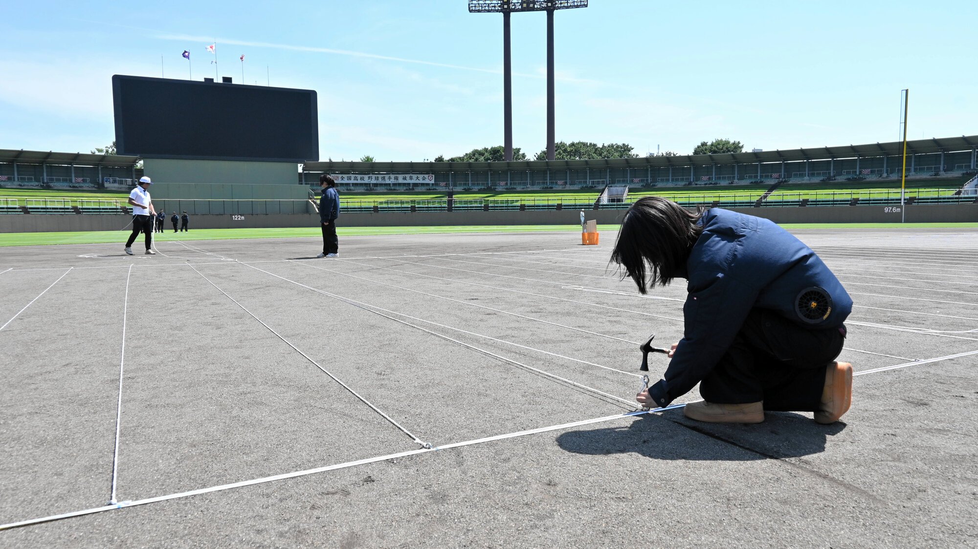 開会式で選手らが並ぶ位置に目印のロープを張る岐南工の土木研究会のメンバーら=ぎふしん長良川
