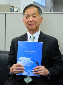 県高校野球史第3版を手にする後藤雅宏さん=大分市