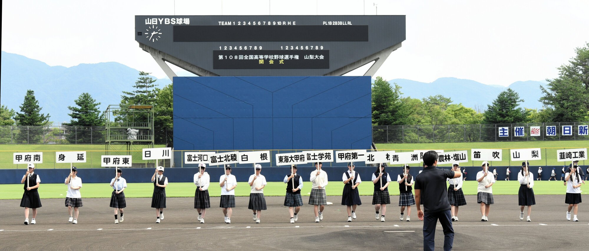 行進のタイミングや立ち位置などをリハーサルで確認する各チームのマネジャーら=2026年7月4日、山日YBS球場、三宅範和撮影