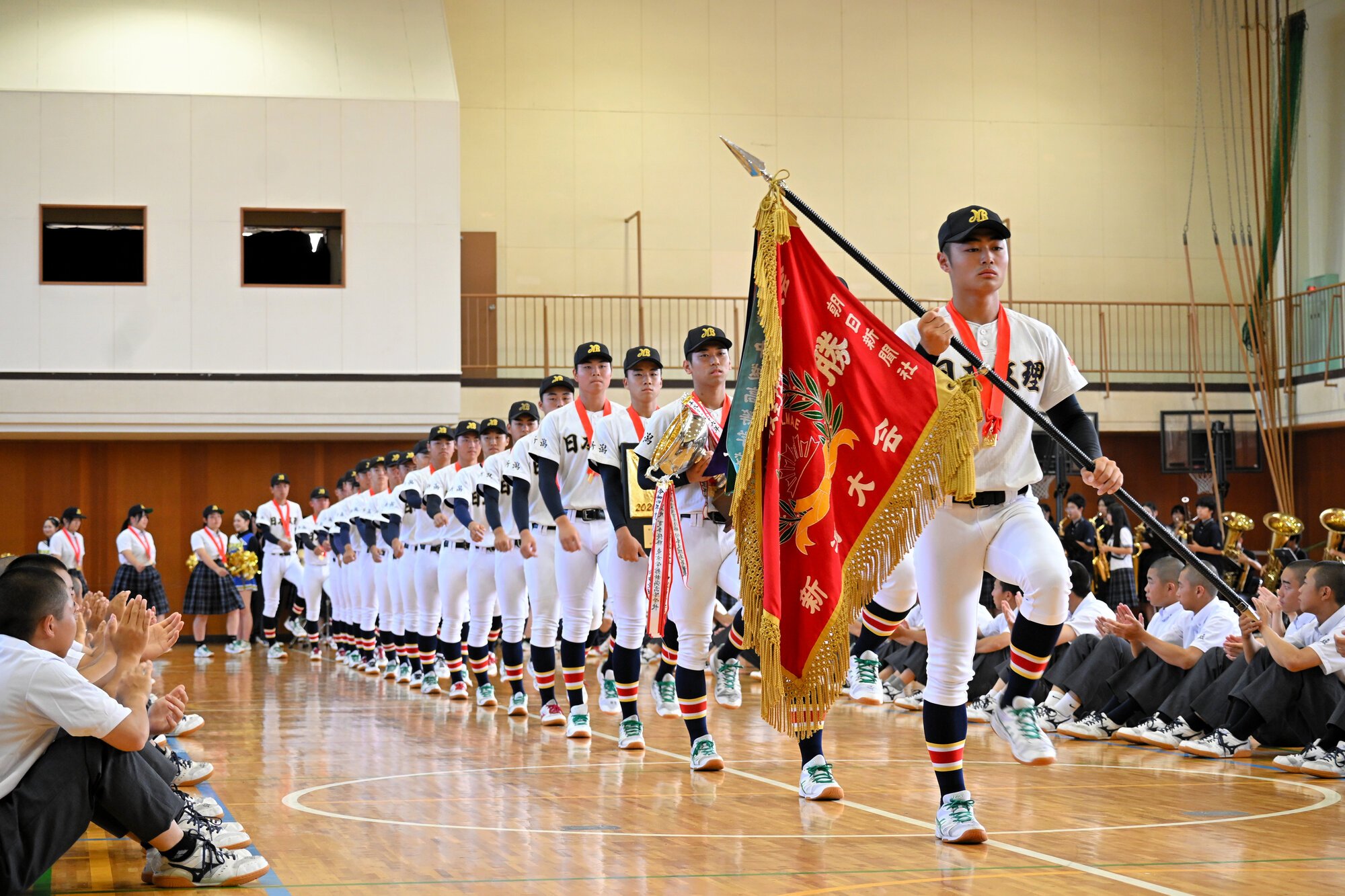 優勝旗を手にした渡部主将を先頭に入場する日本文理の選手たち=2026年7月27日午前8時54分、新潟市西区、久保田正撮影